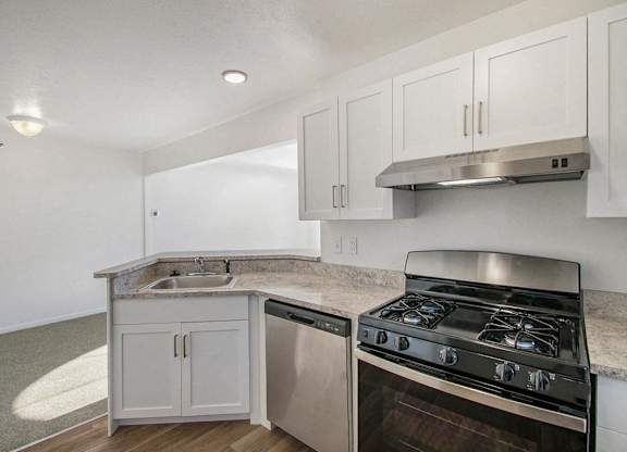 A kitchen with a gas stove, dishwasher, and white cabinets at Brentwood Park Apartments, La Vista, Nebraska