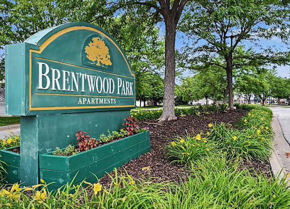 A green sign that says Brentwood Park Apartments in front of trees at Brentwood Park Apartments in LaVista, NE