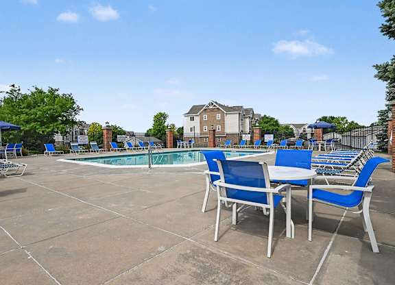 A pool area with blue chairs and a table at Brentwood Park Apartments in LaVista, NE