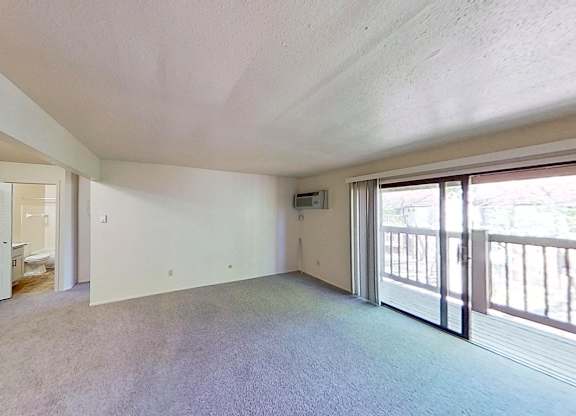 A spacious living room with a private balcony at Briarwood Apartments in Benton Harbor, MI