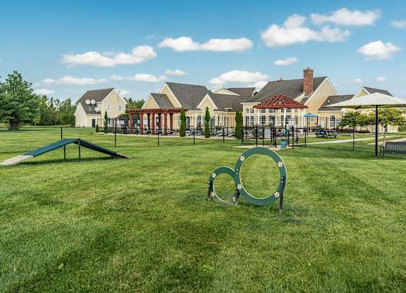 A playground with a green swing set and a large metal ring in the foreground