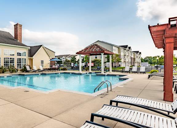 A pool area with sun loungers and a building in the background