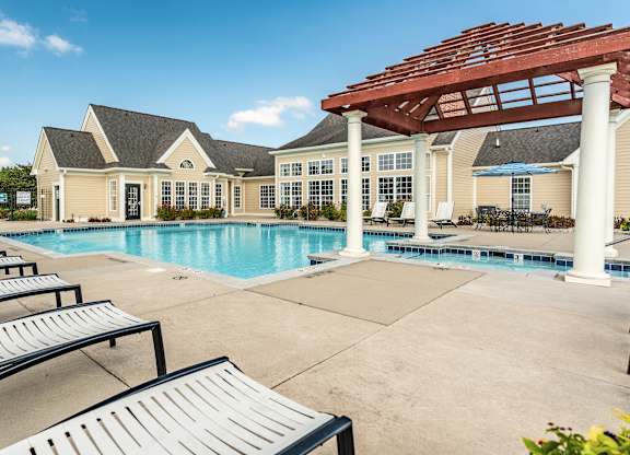 A pool area with sun loungers and a pavilion