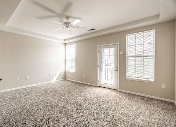 A spacious room with a ceiling fan and carpeted floor