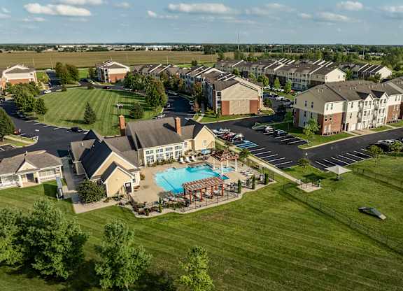 A large grassy area with a swimming pool and apartment buildings in the background