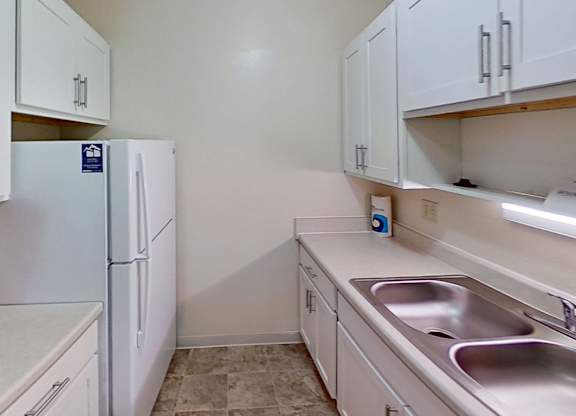 a kitchen with white cabinets and a sink and a refrigerator at Briarwood Apartments, Benton Harbor, 49022