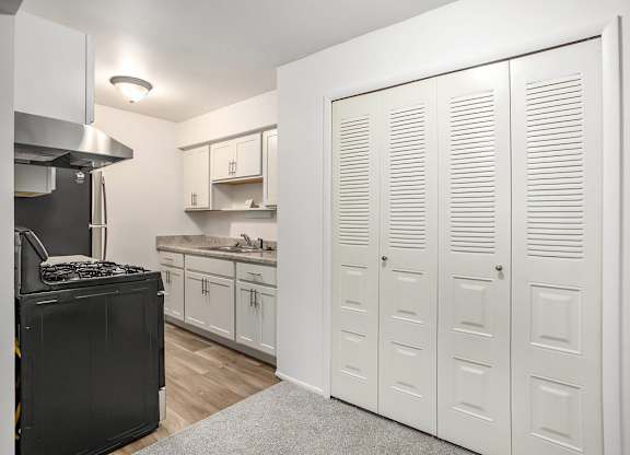 A kitchen with white cabinets and a large closet at Brookside Apartments, Springfield