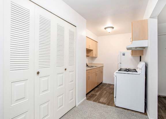 A galley kitchen with white appliances and a closet at Brookside Apartments, Springfield