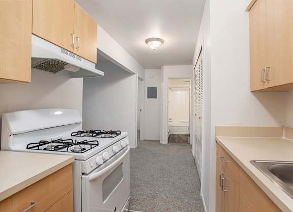 A kitchen with a white stove and wooden cabinets at Brookside Apartments, Springfield