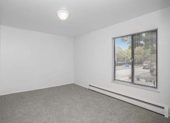 A bedroom with a large window and a grey carpet at Brookside Apartments, Springfield