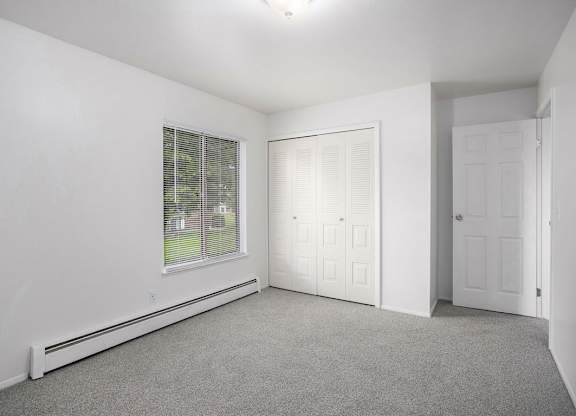 A bedroom with a window with blinds and a closet at Brookside Apartments, Springfield