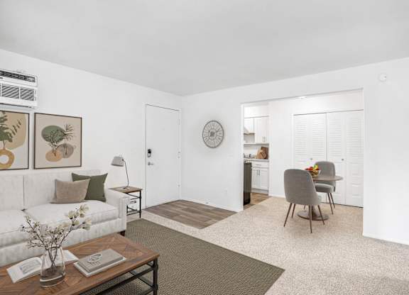 A living and dining room with a couch, a chair, a table, and a clock on the wall at Brookside Apartments, Springfield