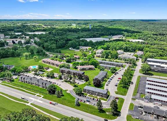 A bird's eye view of a large green campus with buildings and roads.