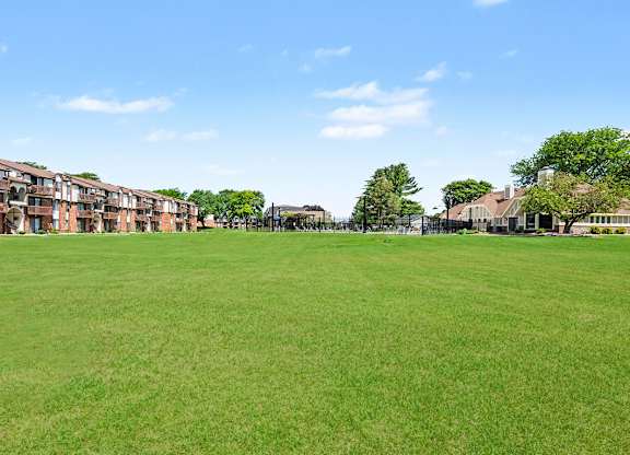 A grassy field with apartment buildings in the background.
