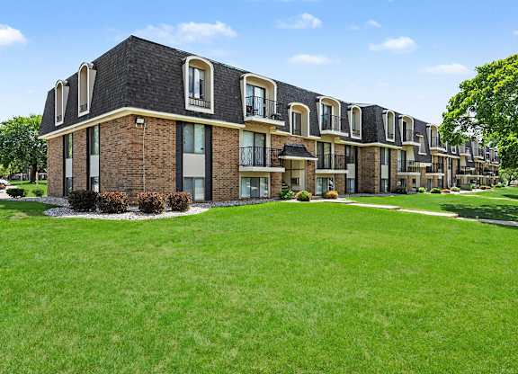 A row of houses with green lawns in front.