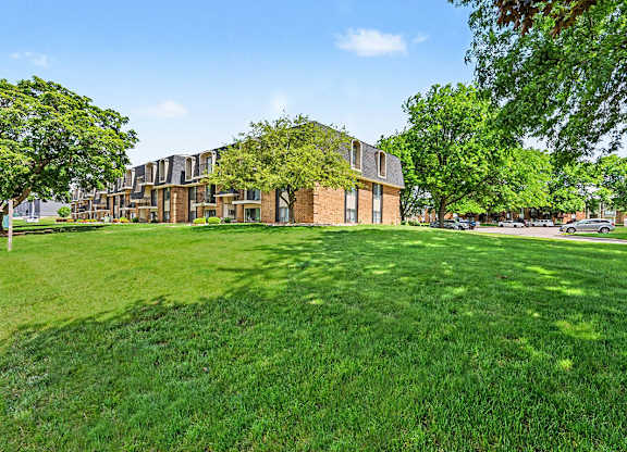 A grassy area in front of a building with trees.