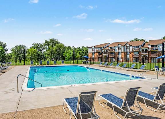 A large swimming pool surrounded by lounge chairs and trees.