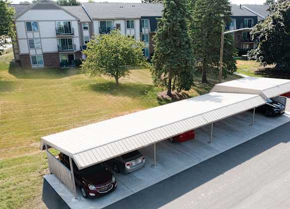 A carport with two cars parked in front of a house.