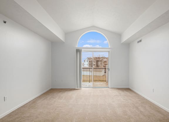 living room with a cathedral ceiling and a door to a balcony  at Black Sand Apartment Homes, Lincoln, 68504