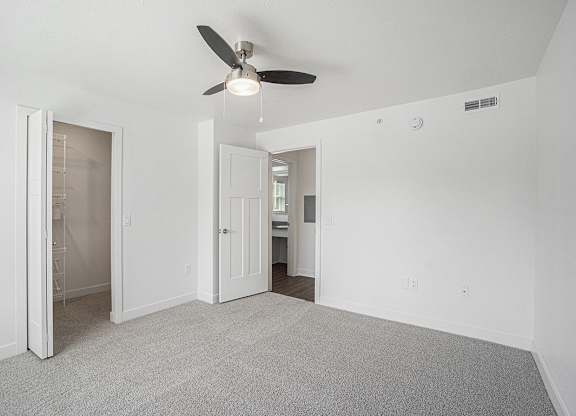 A bedroom with a ceiling fan, walk-in closet, and carpeted floor at Byron Lakes Apartments, Byron Center, Michigan