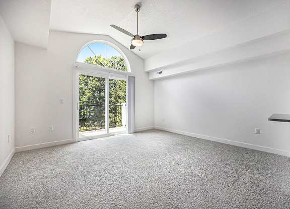 A living room with a ceiling fan and carpeted floor at Byron Lakes Apartments, Byron Center, MI