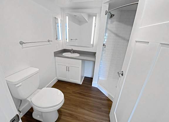 a bathroom with a toilet and a sink and a shower at Byron Lakes Apartments in Byron Center, MI
