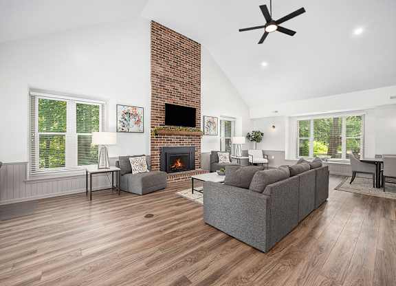 A community building with a fireplace and a grey couch at Byron Lakes Apartments, Byron Center, MI