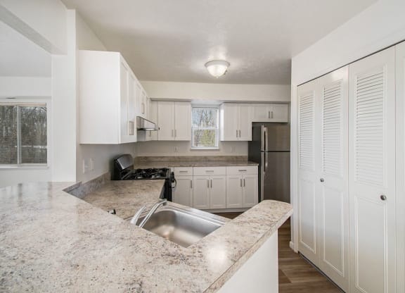 an end style kitchen with white cabinets and a window at Canal 2 Apartments, Lansing, Michigan