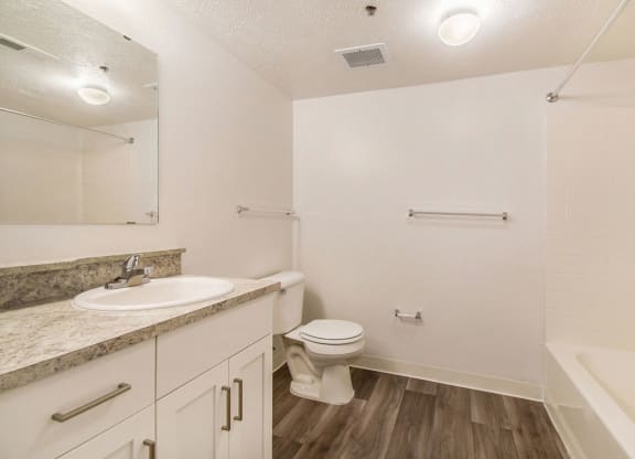 a renovated bathroom with hard surface floors and white cabinetry at Canal 2 Apartments, Lansing, Michigan