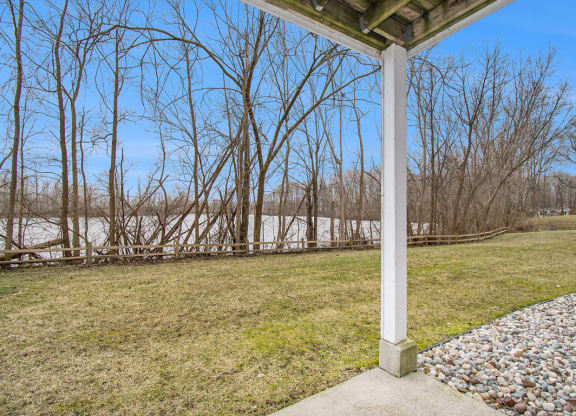 a private patio with a view of a pond and trees at Canal 2 Apartments, Lansing, Michigan