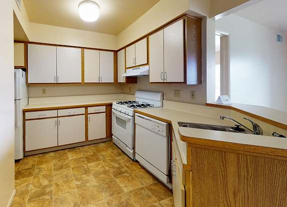 A kitchen with white appliances and wooden cabinets at Canal Club Apartments, Lansing, 48917