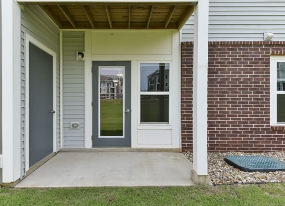 a front porch with a gray door and a red brick wallat Chase Creek Apartment Homes, Alabama