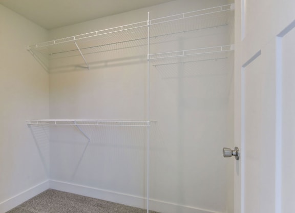 a walk in closet in a bedroom with white walls and a white door at Chase Creek Apartment Homes, Huntsville, 35811