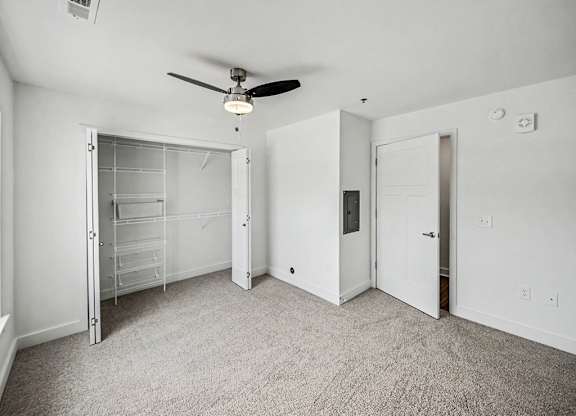 A room with a ceiling fan and carpeted floor.
