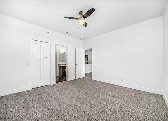 a bedroom with a ceiling fan and a door to a bathroom at Chase Creek Apartment Homes, Huntsville, AL