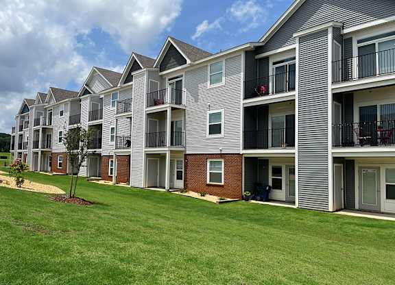 Rear exterior of an apartment building with green grass at Chase Creek Apartment Homes in Huntsville, AL