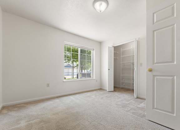 A bedroom with a large window and walk-in closet at Colonial Pointe at Fairview Apartments, Bellevue, 68123