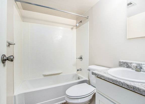 A white bathroom with a toilet, sink, and bathtub at Concord Place Apartments, Kalamazoo, MI