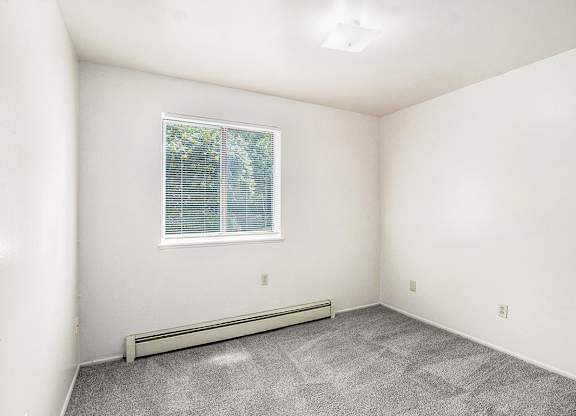 A bedroom with a window and plush carpet at Concord Place Apartments, Kalamazoo, MI
