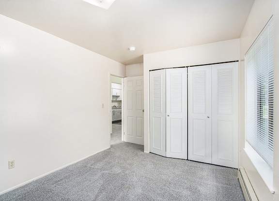 A bedroom with a white closet and a grey carpet at Concord Place Apartments, Kalamazoo, MI