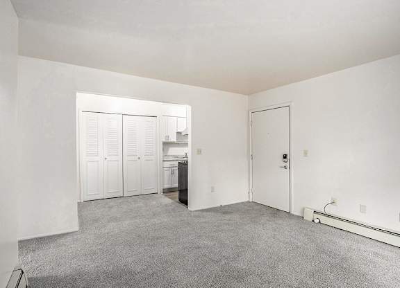 A living and dining room with white closet and carpeted floor at Concord Place Apartments, Kalamazoo, MI