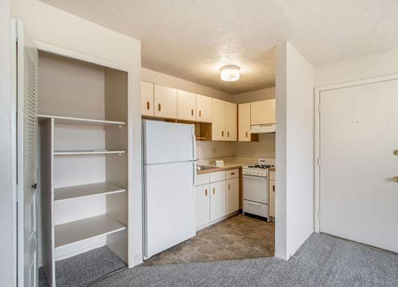 A kitchen with white appliances and a closet with shelves at Concord Place Apartments, Kalamazoo, MI, 49009