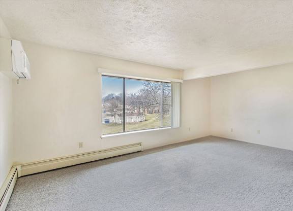 A living area with a large window overlooking trees at Concord Place Apartments, Kalamazoo, MI, 49009