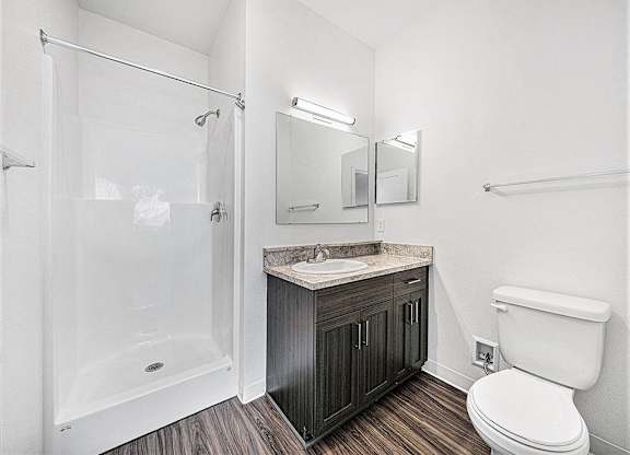 A white toilet sits next to a sink in a bathroom an empty bedroom with a ceiling fan and ensuite at Copper Creek Apartment Homes, Kansas, 67101