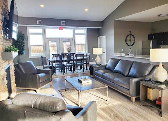 Clubhouse lounge with leather seating and dining space at Copper Creek Homes Apartments, Maize, KS
