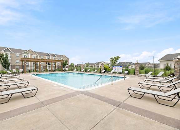 Outdoor swimming pool with lounge chairs and pergola at Copper Creek Homes Apartments, Kansas