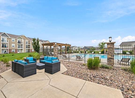 Poolside patio with outdoor seating and iron fence at Copper Creek Homes Apartments, Maize, KS 67101