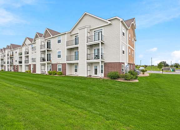 Multi story apartment building with balconies and green lawn at Copper Creek Homes Apartments, Maize, 67101