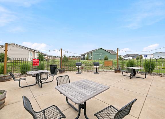 Outdoor barbecue patio with grills and picnic tables at Copper Creek Homes Apartments, Maize, 67101