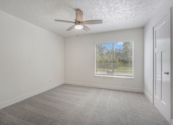 bedroom with a ceiling fan and a large window at The Crossings Apartments, Michigan, 49508
